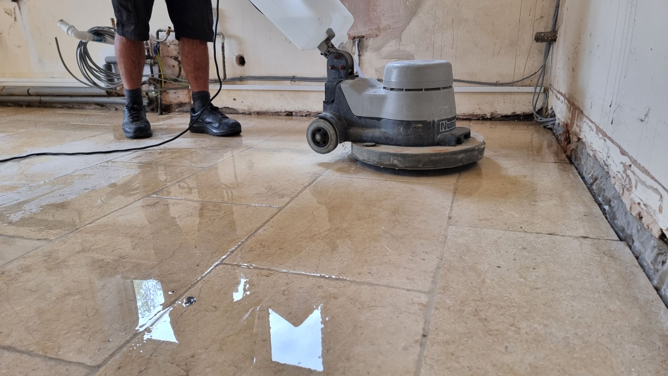 Full image of A floor-cleaning machine is pushed across a glistening limestone floor.