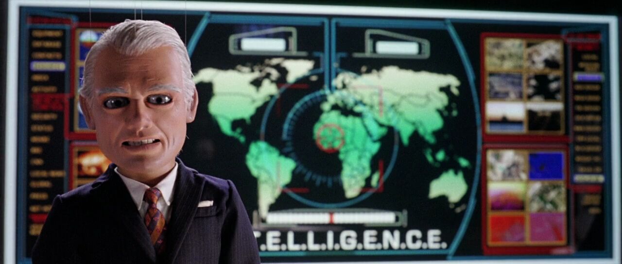 Full image of Scene from Team America: World Police, showing Spottswoode in front of INTELLIGENCE's computer screen, showing a world map.