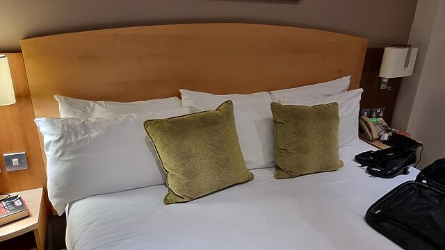 Wide bed with three sets of pillows laid out.