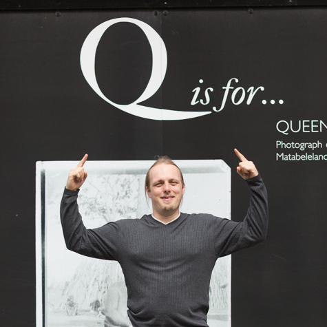 Dan points above his head to a large letter 'Q'.