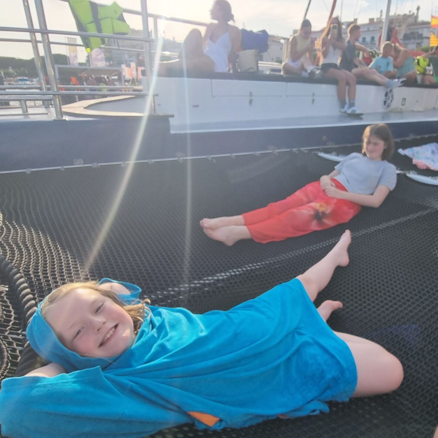 Full image of Children lounge happily in the rigging of a party catamaran.