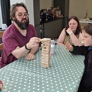 A man carefully positions a block atop a Jenga™️ tower.