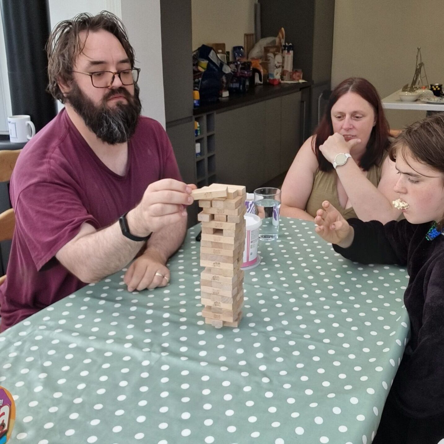 Full image of A man carefully positions a block atop a Jenga™️ tower.