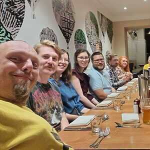 A row of volunteers sit at a dining table.