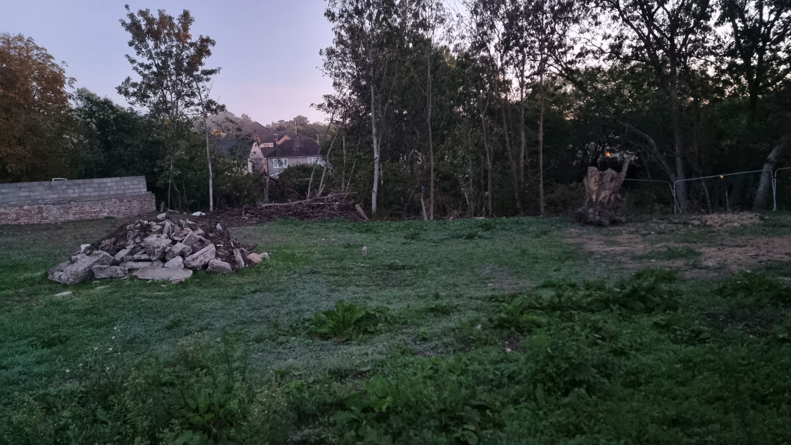 Full image of The tree stump and rubble seen from 'over' the fence, from a different angle.