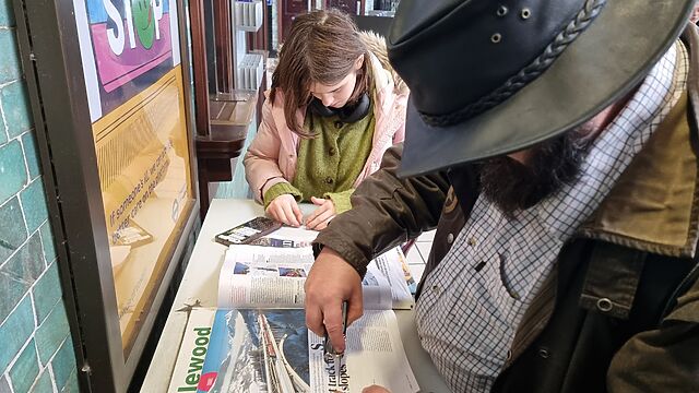A man and a tweenager work together to cut words from a magazine.