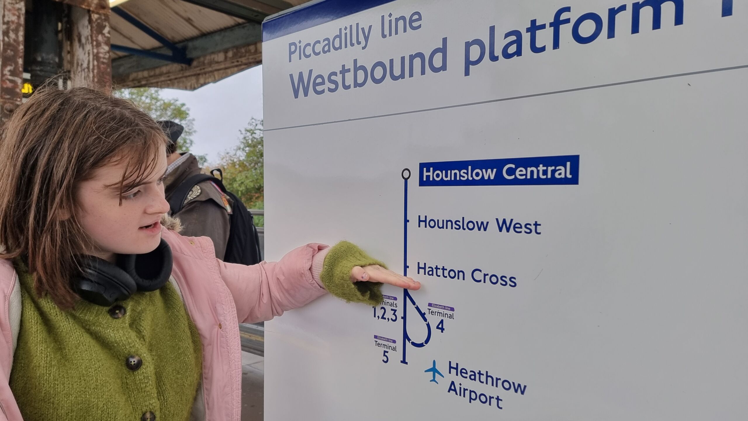Full image of A tweenager indicates on a freestanding map the point on the Piccadilly Line at which Heathrow Airport begins.