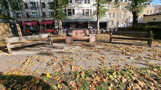 Three park benches with engravings and a sculpture of a cat sitting on a book.