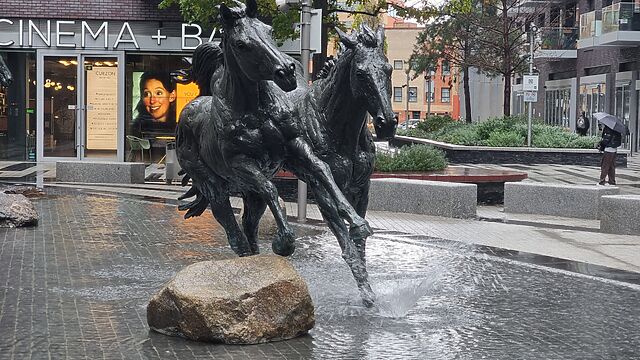 Statue of two horses with small fountains giving the appearance of them kicking up water as they run.