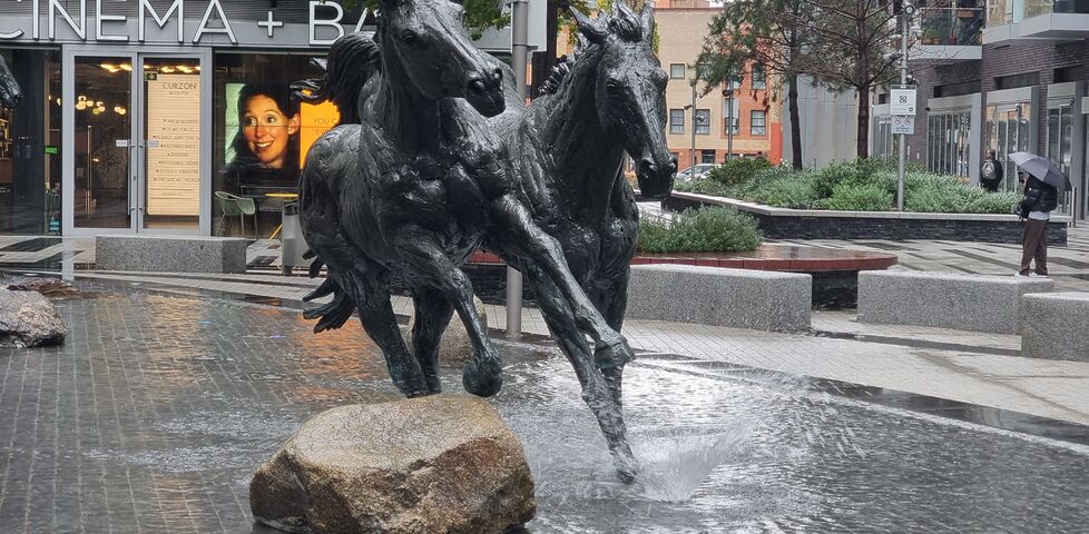 Statue of two horses with small fountains giving the appearance of them kicking up water as they run.