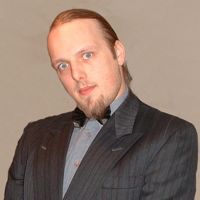 Dan, in his mid-20s, wearing a dark grey suit and light grey shirt.