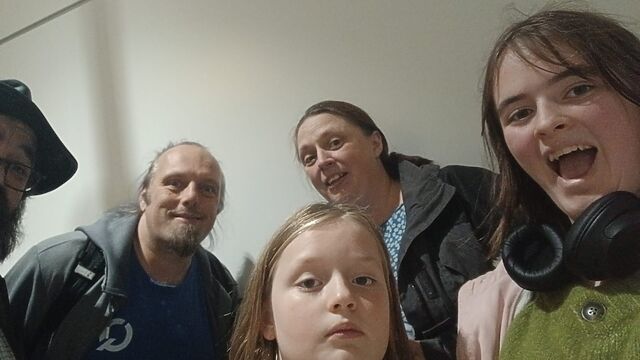 A family smiles for the camera in an generic-looking airport corridor.